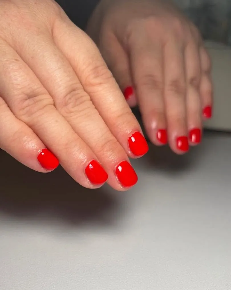 Glossy true-red Bio Sculpture gel manicure on short rounded nails